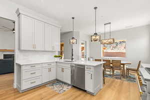 Kitchen featuring stainless steel appliances, decorative light fixtures, white cabinetry, and light wood-style floors