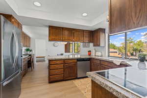 Kitchen with stainless steel appliances, a tray ceiling, light granite countertops,  and a peninsula