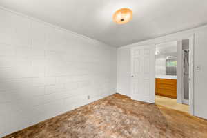 Unfurnished bedroom with concrete block wall and carpet