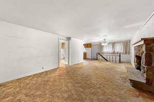 Unfurnished living room featuring carpet flooring, a fireplace, and ceiling fan