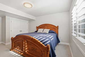 Bedroom with light colored carpet and a closet