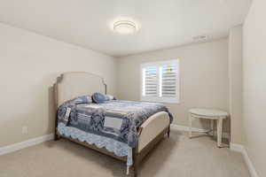 Bedroom with light colored carpet and a textured ceiling