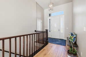 Entrance foyer featuring light wood finished floors, a high ceiling, and hanging lights