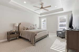 Bedroom featuring light carpet, ceiling fan, recessed lighting, and a tray ceiling