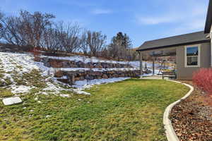 Snowy yard with a ceiling fan, a patio area, and a lawn