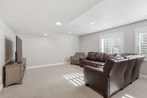 Living area with light colored carpet, a textured ceiling, and recessed lighting