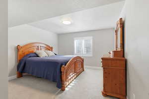 Bedroom with light colored carpet and a textured ceiling