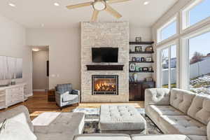 Living area featuring a ceiling fan, a stone fireplace, wood finished floors, and recessed lighting