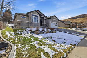 Craftsman-style home featuring stone siding, concrete driveway, a garage, and a residential view