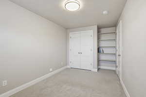 Unfurnished bedroom with light carpet, a closet, and a textured ceiling