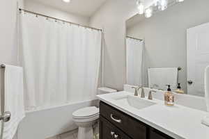 Full bathroom with vanity, shower / bathtub combination with curtain, and recessed lighting