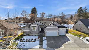 View of front of house featuring a garage, concrete driveway, a residential view, a mountain view, and stone siding