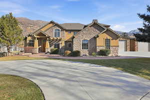 Craftsman-style home featuring curved driveway, a front lawn, stone siding, and stucco siding