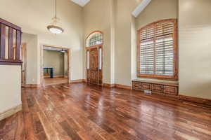 Foyer with dark wood-style floors, a high ceiling, and ceiling fan