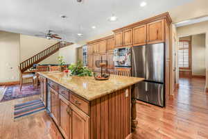 Kitchen with stainless steel appliances, wood finish cabinets, pendant lighting, light stone countertops, and light wood-type flooring