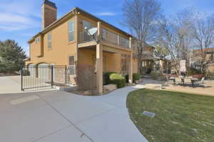 Rear view of property featuring stucco siding, a garage, driveway, a chimney, and a yard