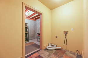 Laundry room featuring electric dryer hookup, dark stone finish floors, hookup for a washing machine, and a textured wall