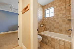 Full bathroom featuring tiled shower / bath, a ceiling fan, tile patterned floors, and carpet