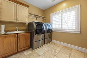 Laundry room with cabinet space, washing machine and clothes dryer, and light stone finish flooring
