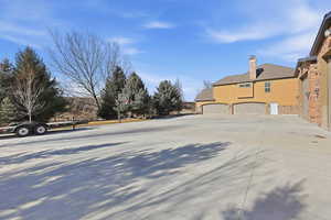 View of property exterior with stone siding, a garage, stucco siding, concrete driveway, and a chimney