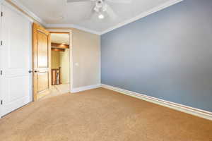 Unfurnished bedroom featuring crown molding, carpet, and ceiling fan