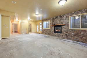 Unfurnished living room with a textured ceiling, concrete flooring, and a large fireplace