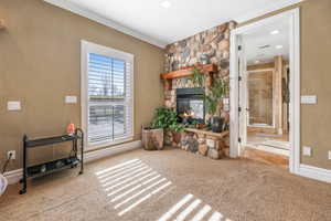 Living area with crown molding, a stone fireplace, carpet, and recessed lighting