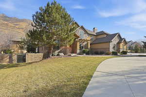 View of front of house with stone siding, a gate, a chimney, stucco siding, and a mountain view