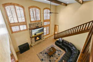 Carpeted living room with a fireplace and ceiling fan