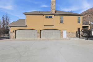 View of side of property featuring stone siding, stucco siding, concrete driveway, and an attached garage