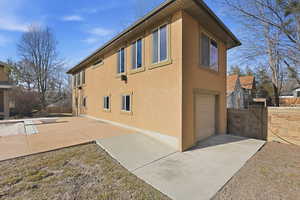 View of property exterior with an attached garage, stucco siding, and a gate
