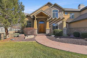 Craftsman house with stone siding, stucco siding, a front lawn, and a chimney