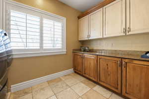Kitchen featuring dark stone counters, wood finish cabinetry, and stone tile floors