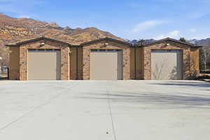 View of front of property with a mountain view, stone siding, driveway, and stucco siding
