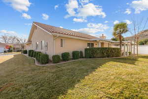 View of side of property with stucco siding, a tile roof, and a chimney