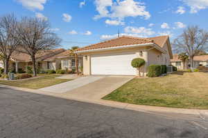 Ranch-style house featuring a tiled roof, a front yard, stucco siding, concrete driveway, and a garage
