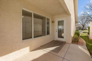 View of exterior entry with stucco siding and a patio