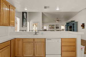 Kitchen with tile countertops, dishwasher, open floor plan, a peninsula, and a textured ceiling