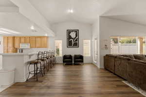 Kitchen featuring open floor plan, a breakfast bar, light brown cabinets, vaulted ceiling, and light countertops