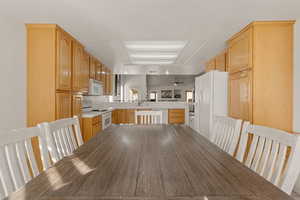 Kitchen with light brown cabinets, ceiling fan, white appliances, light countertops, and a peninsula