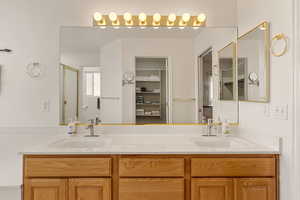 Full bathroom featuring double vanity, a stall shower, and a walk in closet