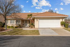 View of front of house with stucco siding, concrete driveway, a tile roof, and a front lawn