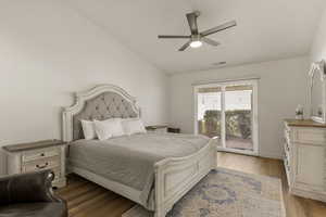 Bedroom featuring light wood-style flooring, access to outside, vaulted ceiling, and a ceiling fan
