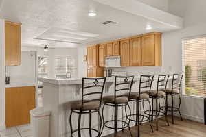 Kitchen featuring recessed lighting, a breakfast bar, tile counters, white appliances, and a ceiling fan
