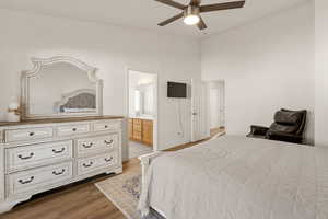 Bedroom with light wood finished floors, a ceiling fan, a towering ceiling, and connected bathroom