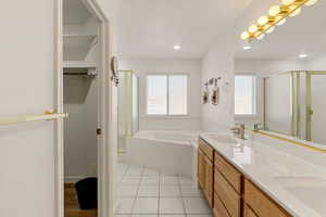 Bathroom with a bath, a stall shower, a spacious closet, and double vanity