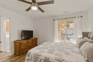 Bedroom with light wood-style floors, a ceiling fan, and washer / dryer