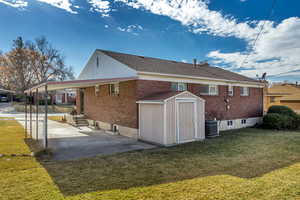 Back of house featuring a shed, a yard, brick siding, and a porch