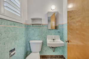 Half bathroom featuring a wainscoted wall and tile walls
