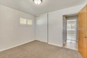 Unfurnished bedroom with light colored carpet, a closet, and multiple windows